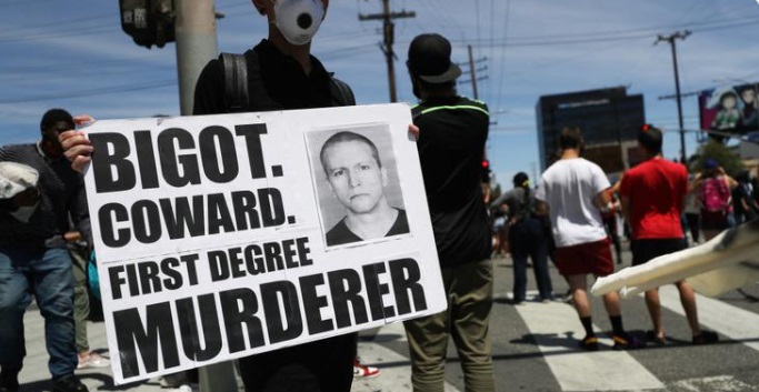 PHOTO Protester In The Streets Holding Sign That Says Bigot Coward First Degree Murderer Referring To Derek Chauvin