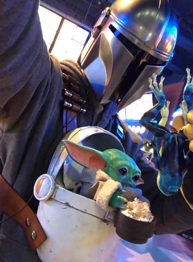 PHOTO Baby Yoda Reaching For A Bowl Of Popcorn While The Mandalorian Holds Him