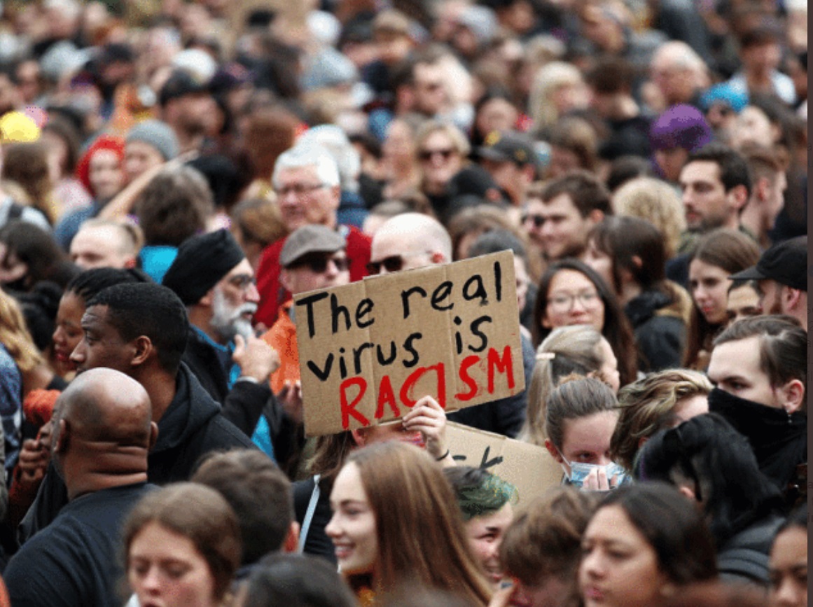 PHOTO Women Without Mask Holding Sign That Says The Real Virus Is Racism