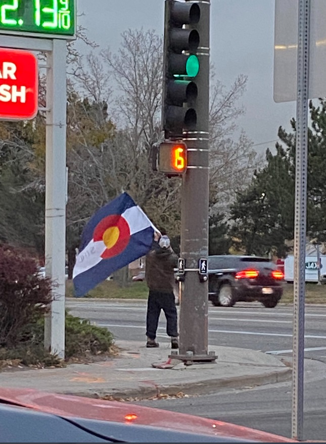 PHOTO Man Outside Greeting Residents With Colorado Flag In Freezing Temperatures In Estes Park