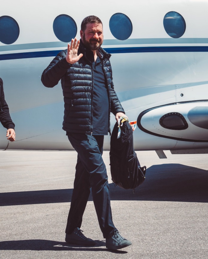 PHOTO Chris Beard Walks Off Plane In Austin Wearing Winter Jacket And Holding Backpack In 70 Degree Weather