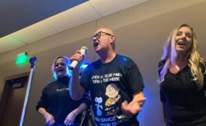 PHOTO Peter Robbins Singing Into A Microphone While Wearing A Charlie Brown Shirt