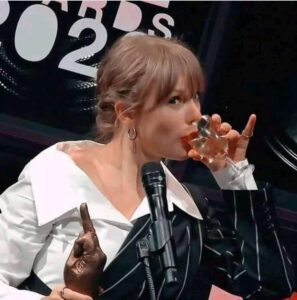 PHOTO Taylor Swift Drinking Wine While Holding A Statue Of A Middle Finger