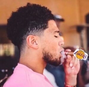 PHOTO Devin Booker Mocking The Lakers By Smoking A Cigar With Their Logo On It Meme