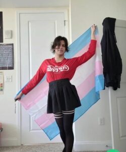 PHOTO Salvador Ramos Wearing A Dress With Tights And A Coca Cola Blouse While Holding Multi-Colored Flag