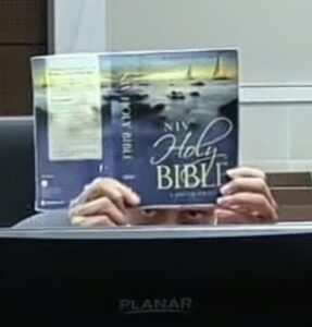 PHOTO Darrell Brooks Pretending To Read A Bible In Court And Peaking At What Is Happening From Underneath It