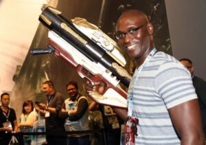 PHOTO Lance Reddick Holding A Massive Golden Gun While Filming Movie