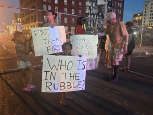 PHOTO Of Protesters Signs Outside Collapsed Apartment Building In Davenport Iowa