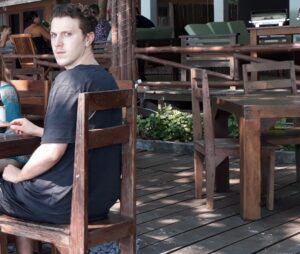 PHOTO Rickard Andersson Awkwardly Sitting In A Wooden Chair During A Group Dinner