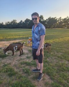 PHOTO Jamie White Drinking Beer While Goats Eat Grass Around Him In Austin