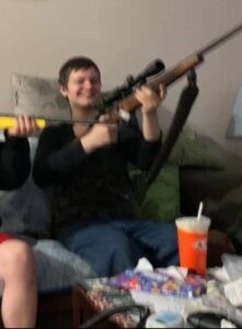 PHOTO Jesse Strang Holding A Gun Indoors On A Couch